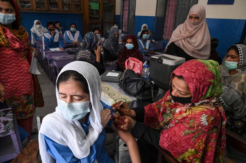 A health worker inoculates a student with a vaccine against the Covid-19 coronavirus at a school in Lahore after the government began to vaccinate children from the age of 12.  AFP