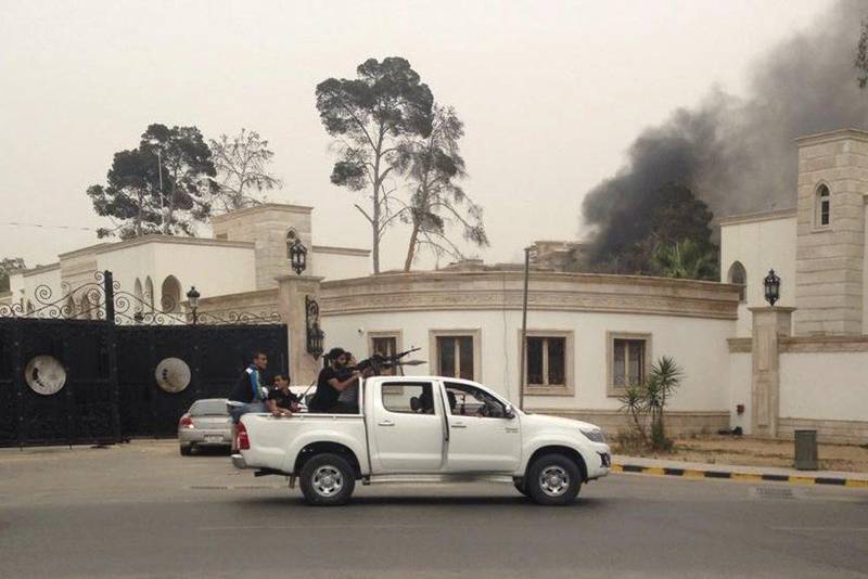 Armed men aim their weapons from a vehicle as smoke rises in the background near Libya’s General National Congress in Tripoli on May 18, 2014. Heavily armed gunmen stormed into Libya’s parliament on Sunday after attacking the building with anti-aircraft weapons and rocket-propelled grenades, witnesses and residents said. Reuters