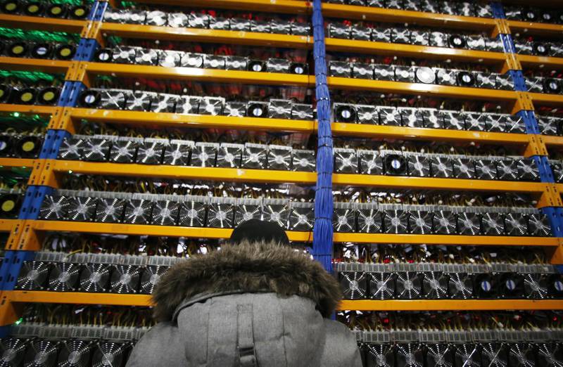 An employee checks the fan on a mining machine at the Bitfarms cryptocurrency farming facility in Farnham, Quebec, Canada, on Wednesday, Jan. 24, 2018. Bitfarms says it's making more than $250,000 a day from minting Bitcoin, other virtual currencies and fees at four sites in the province. Photographer: Christinne Muschi/Bloomberg