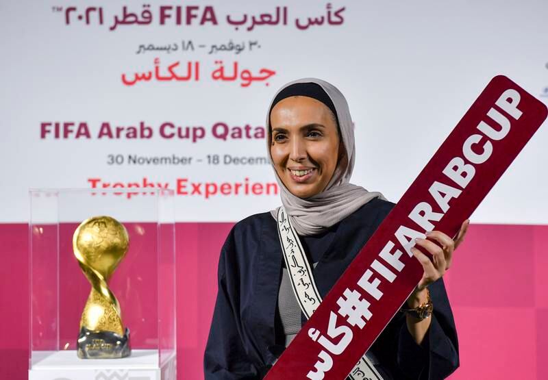 A woman poses next to the Fifa Arab Cup Trophy.