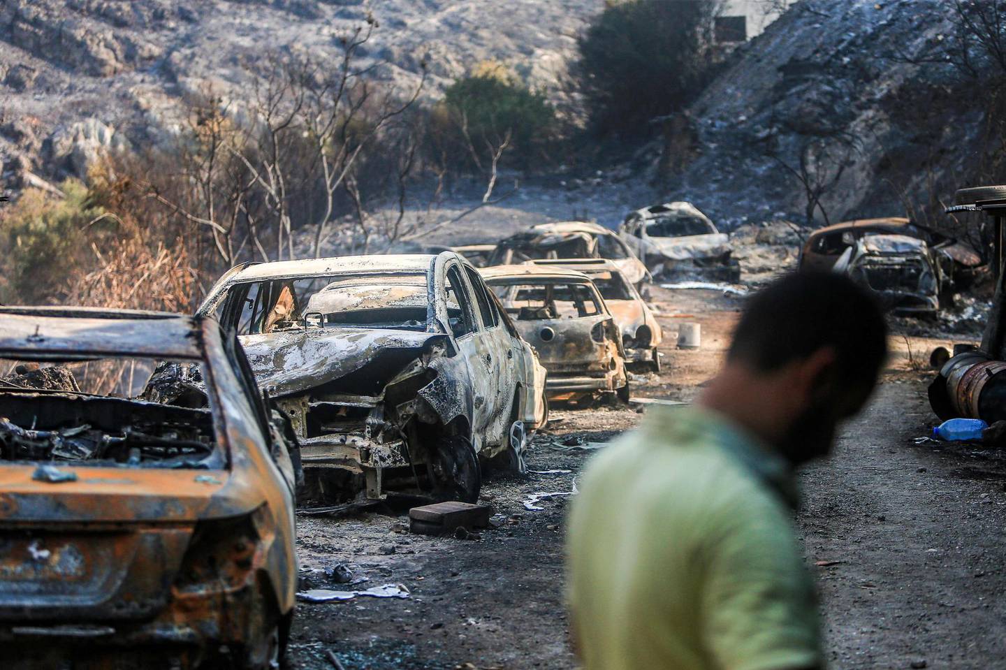 This picture taken on October 15, 2019 shows vehicles lying on the side of a road, after they were burnt by fires near the town of Damour in Lebanon's Shouf mountains southeast of the capital. Flames devoured large swaths of land in several Lebanese and Syrian regions. The outbreak coincided with high temperatures and strong winds, according to the official media in both countries. / AFP / -
