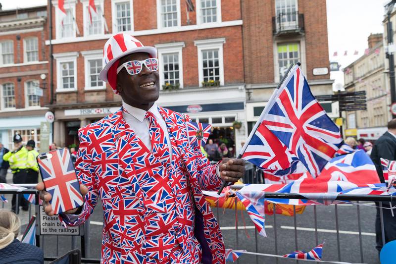 Royal fan Joseph Afrane from south London waves a flag as he waits for Britain's Princess Eugenie and her husband Jack Brooksbank to ride past in a horse-drawn carriage. EPA