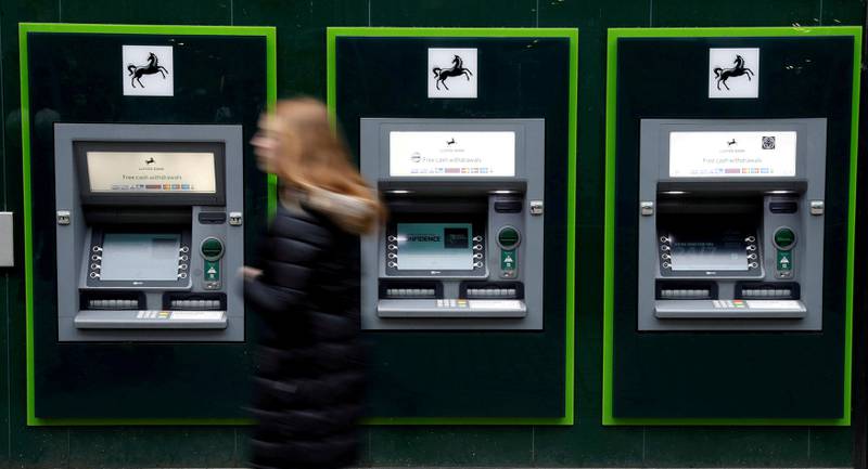 FILE PHOTO: A woman walks past a row of cash machines outside a branch of Lloyds Bank in Manchester, Britain, February 21, 2017.   REUTERS/Phil Noble/File Photo
