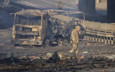 A Ukrainian soldier walks past debris of a burning military truck, on a street in Kiev. AP