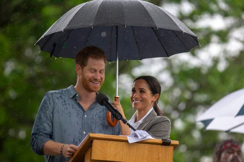 Meghan holds an umbrella for Prince Harry as he addresses the public during a Community Event in Dubbo, Australia, in October 2018. Getty Images