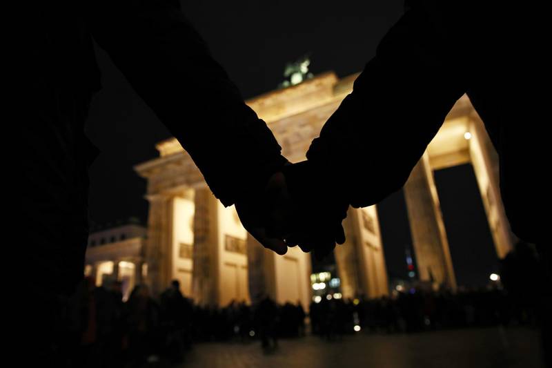People hold hands during a vigil at the Brandenburg Gate to commemorate the victims of the Hanau shootings in Berlin, Germany. A local man named Tobias Rathjen is the main suspect in having shot dead nine people last night at two hookah bars in Hanau, and killing possibly his mother and then himself later on when police prepared to raid his apartment. Police suspect a right-wing motive to the attacks. Getty Images
