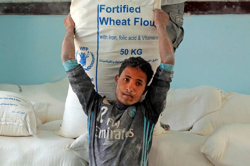 Yemenis receive humanitarian aid provided by the World Food Programme (WFP) in the Yemeni capital Sanaa on June 1, 2021. / AFP / MOHAMMED HUWAIS
