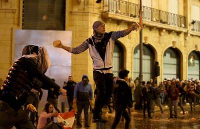 A Lebanese anti-government protester hurls stones at riot police. AFP