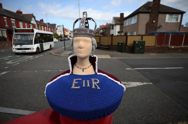 A knitted figure of the queen is displayed on top of a post box in Wallasey. Reuters