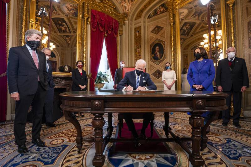 US President Joe Biden signs documents in the President's Room at the US Capitol following the inauguration ceremony. Bloomberg