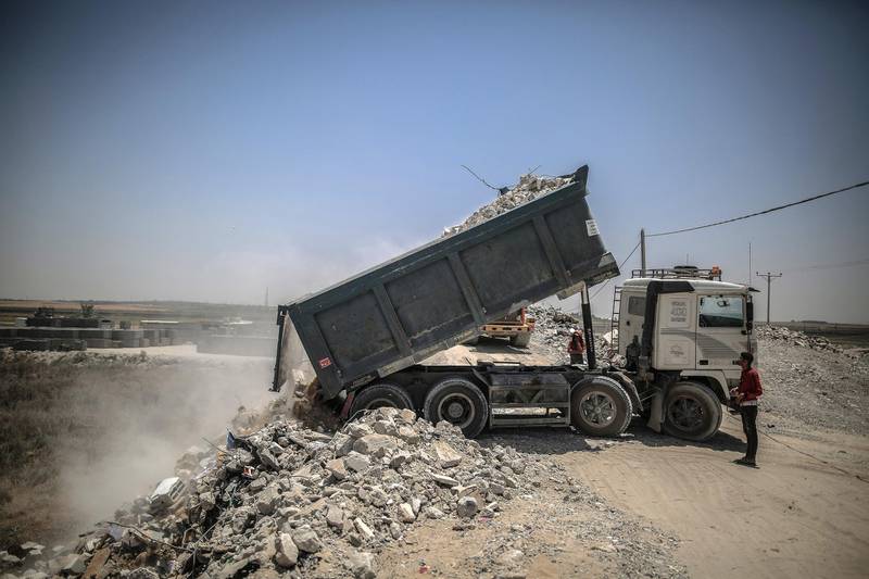 Workers deliver the rubble of buildings destroyed during the May rocket attacks. Sanad Latefa for The National