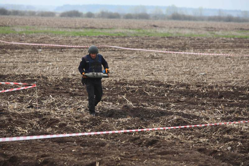 A member of a demining team of the State Emergency Service of Ukraine carries an unexploded projectile during mine clearing near Brovary, north-east of Kyiv. AFP