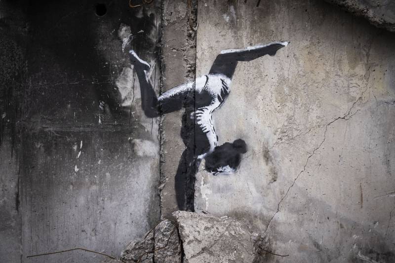 A Banksy artwork of a woman in a leotard doing a handstand is seen on the wall of a destroyed building in Borodyanka. Getty.