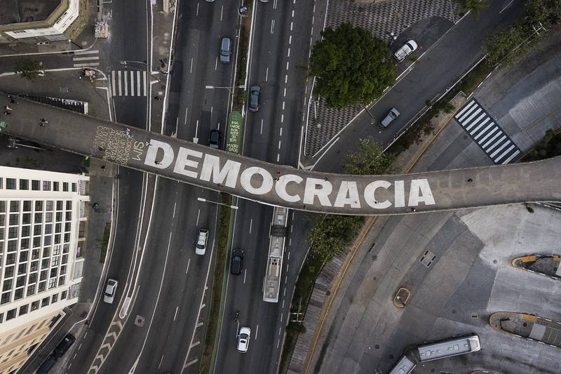 People walk on a pedestrian bridge that has text written on it that reads in Portuguese "Democracy", in Sao Paulo, Brazil.  The country is set for a presidential run-off election scheduled for October  30. AP