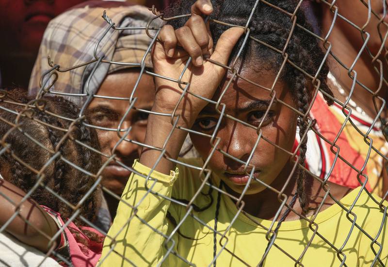 An Ethiopian refugee who fled fighting in Tigray waits behind a fence in a camp in Sudan.