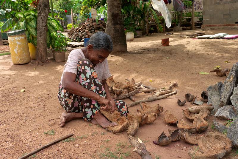 A woman takes the fibre from a coconut shell in Waikkal village, Sri Lanka.