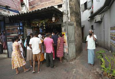 People queue for essentials at a shop before the beginning of the curfew, in Colombo. AP