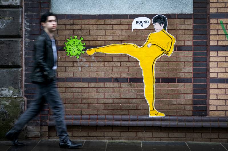 A picture by street artist 'Palley' in Glasgow's East End shows Bruce Lee kicking a coronavirus molecule. PA