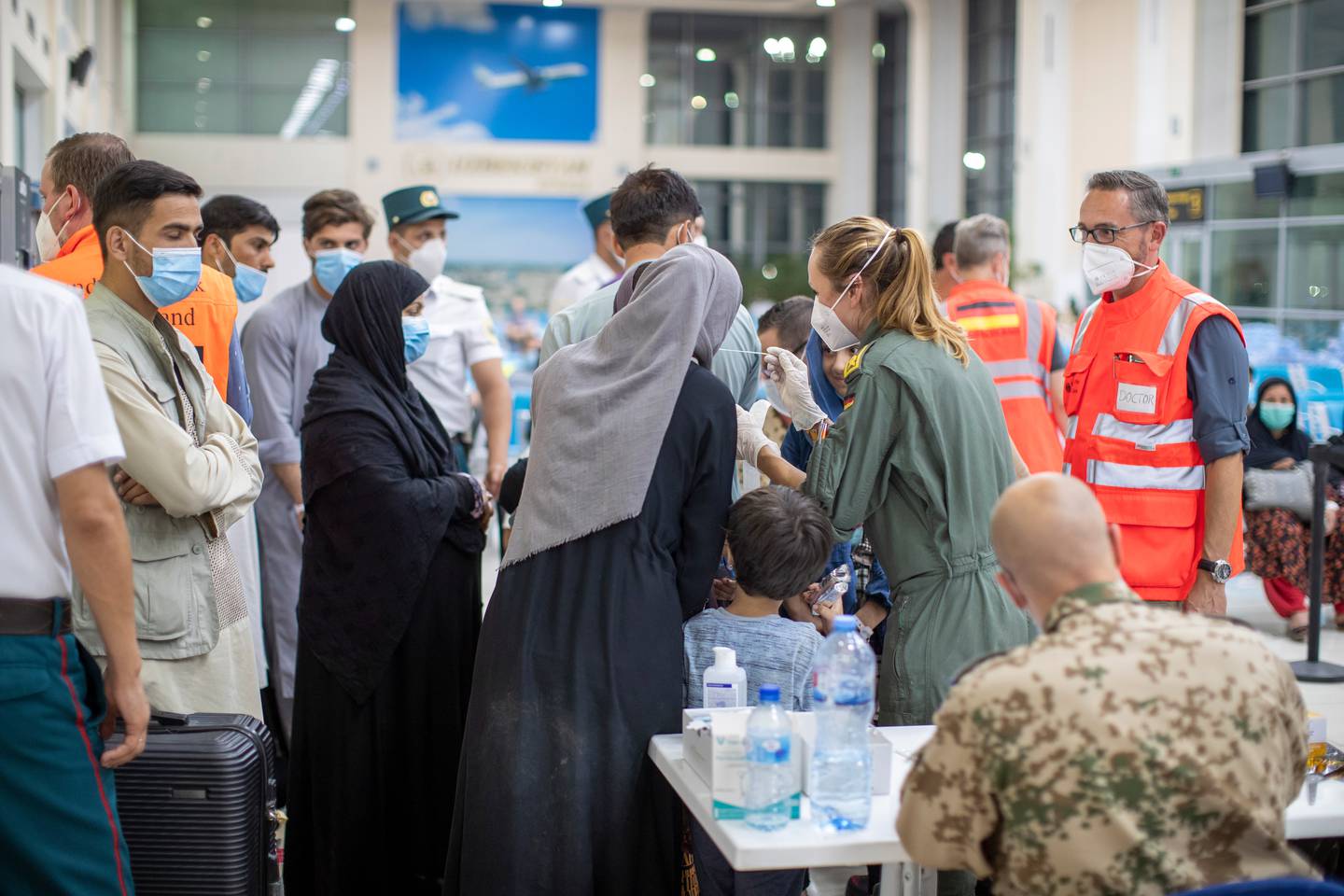 People flown from Afghanistan are tested for Covid-19 by German military personnel. Photo: EPA 