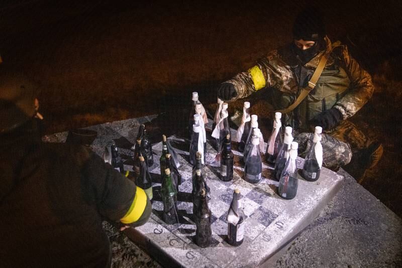 Members of a Territorial Defence unit play checkers with Molotov cocktails while guarding a barricade on the outskirts of Kyiv. Getty Images