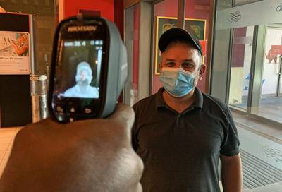 A man, wearing protective masks to prevent the spread of the coronavirus, has his temperature taken at the Ibn Battuta mall in the Emirate of Dubai on April 27, 2020. The United Arab Emirates decided on April 23 to reopen malls, cafes and restaurants and ease lockdown restrictions imposed last month to prevent the spread of coronavirus on the occasion of Ramadan. / AFP / GIUSEPPE CACACE
