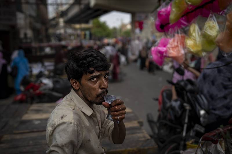 A roadside vendor drinks water from a plastic pouch at a weekly market in New Delhi. AP