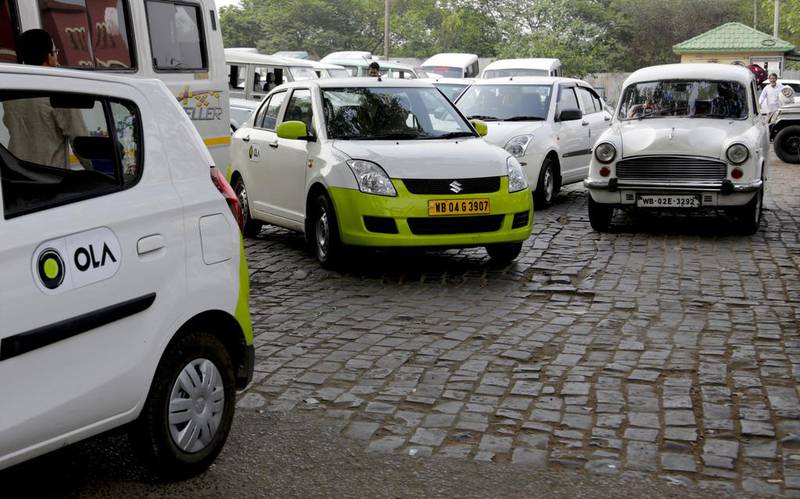 Ola cabs, left, wait for customers in Kolkata. Bikas Das / AP Photo