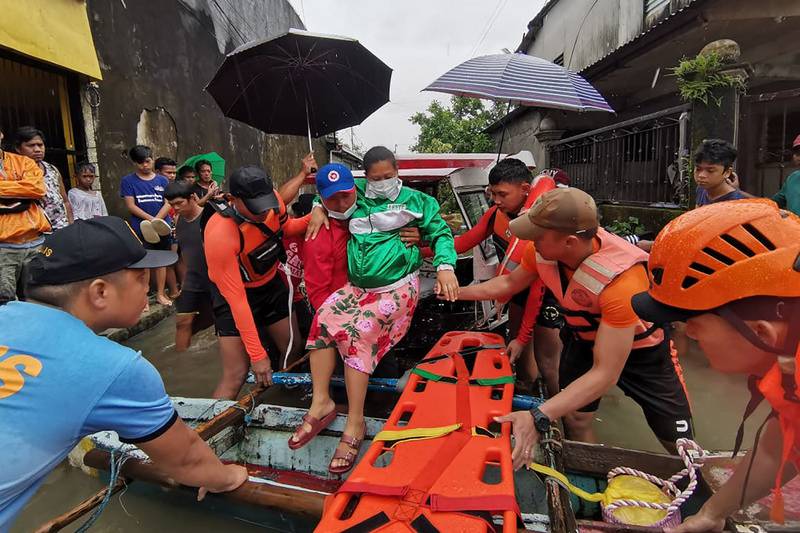 This undated handout photograph received from the Philippine Coast Guard (PCG) on April 11, 2022 shows coast guard and police personnel evacuating a resident from a flooded area in Abuyog town, Leyte province, southern Philippines, following heavy rains brought about by Tropical storm Agaton.  (Photo by Philippine Coast Guard (PCG)  /  AFP)  /  -----EDITORS NOTE --- RESTRICTED TO EDITORIAL USE - MANDATORY CREDIT "AFP PHOTO  /  PHILIPPINE COAST GUARD (PCG) " - NO MARKETING - NO ADVERTISING CAMPAIGNS - DISTRIBUTED AS A SERVICE TO CLIENTS