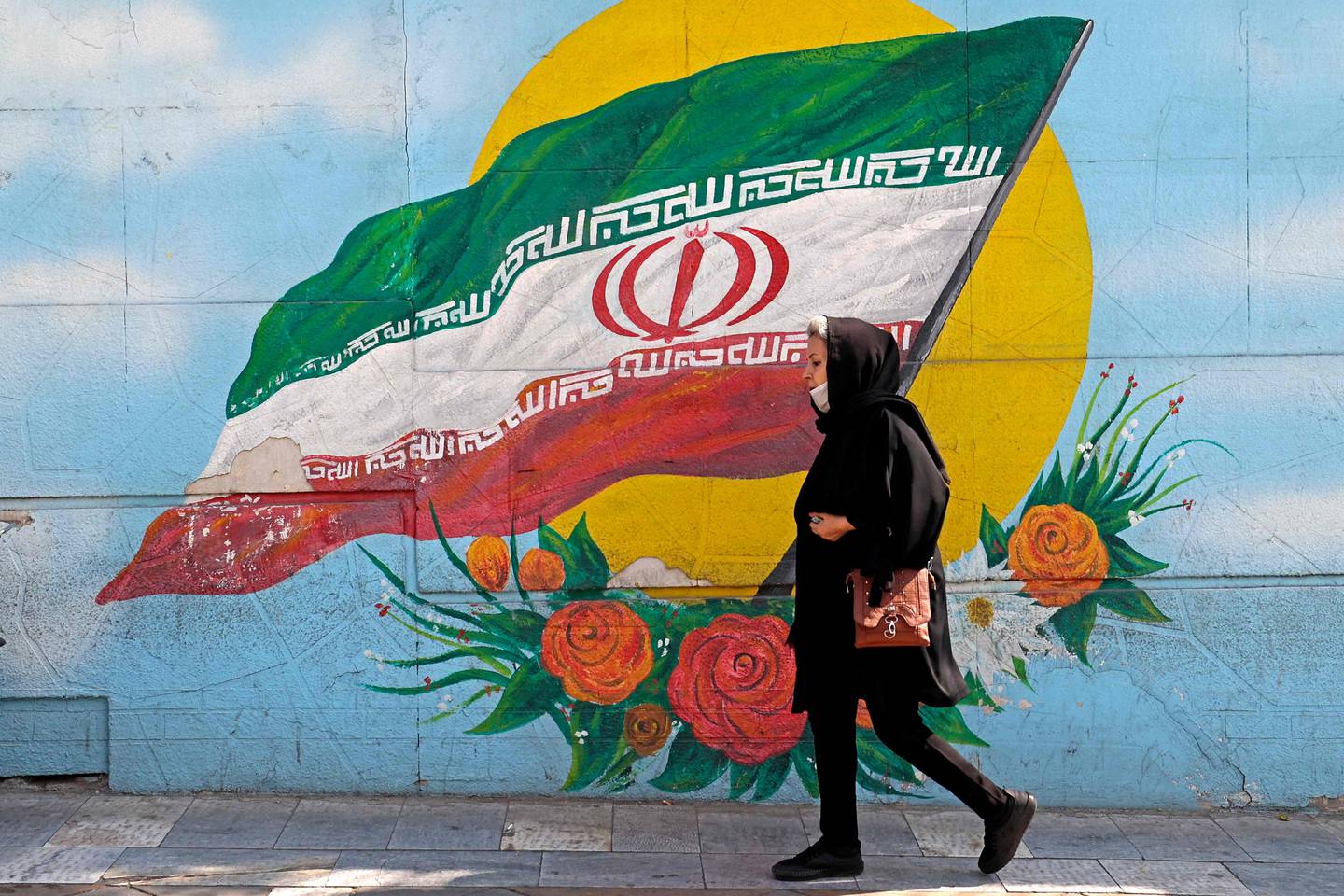 A woman walks past a mural in the Iranian capital, Tehran. AFP