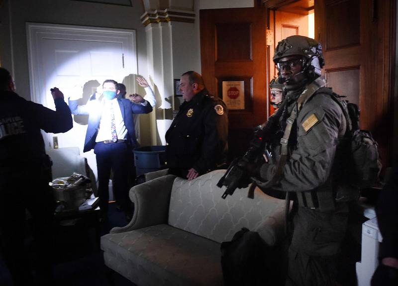 Congress staffers hold up their hands while Capitol Police Swat teams check everyone in the room as they secure the floor of Trump supporters. AFP