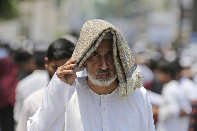 A man tries to protect himself from the sun after prayers at Mecca mosque in Hyderabad, India. AP Photo