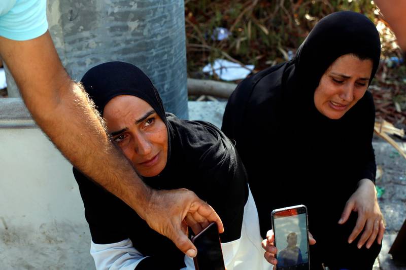 Zeinab Zer Eldin, left, and her sister-in-law shows a photo of her missing husband near the site of the explosion in the port of Beirut. AP Photo