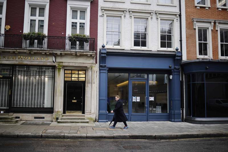 A pedestrian passes closed shop fronts in Mayfair, central London. AFP