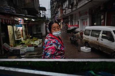 A woman stands at an access point to a neighborhood closed off by barriers in Wuhan, China's central Hubei province.  AFP