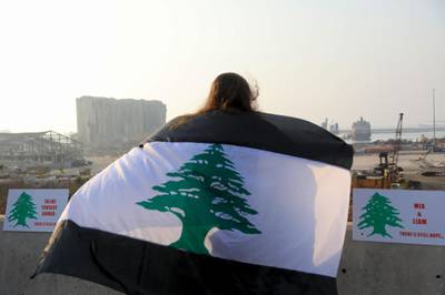 A woman, draped in a black-striped Lebanese flag, looks at the site of the massive explosion at Beirut's port area, during a demonstration to mark one month since the cataclysmic August 4 explosion that killed 191 people, in the Lebanese capital Beirut. AFP