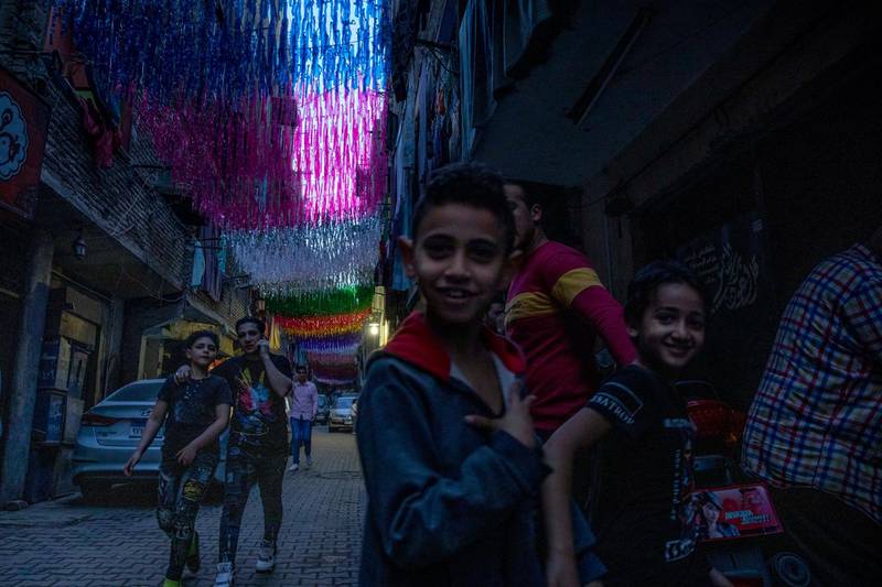 Children walk under decorations hung up for Ramadan a day ahead of the holy month, in the Imbaba neighborhood of Giza, April 23, 2020. Muslims around the world are trying to maintain the cherished rituals of Islam holiest month during the coronavirus pandemic.  (AP Photo/Nariman El-Mofty)