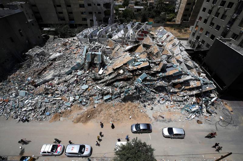 Pedestrians and cars pass the remains of a tower building destroyed by Israeli missile strikes in Gaza City. Reuters