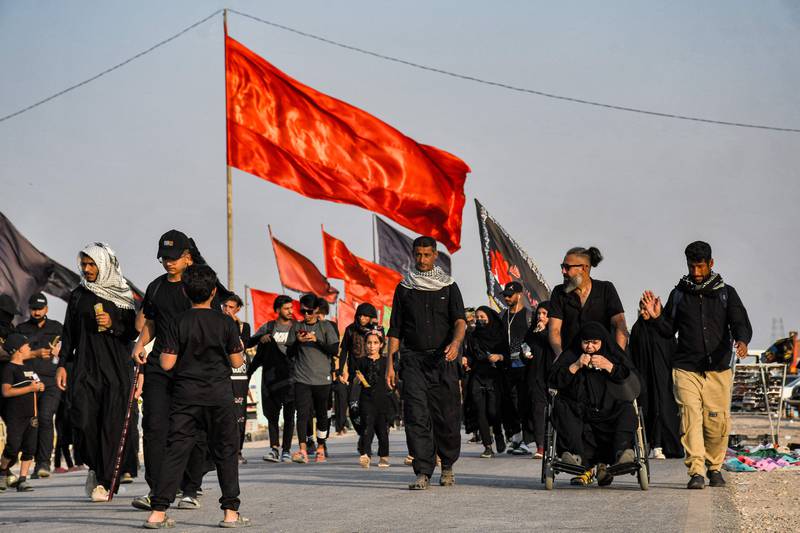 Shiite Muslim pilgrims march with flags en route to Karbala from Nasiriyah in Iraq's southern Dhi Qar province on September 5, 2022, before the Arbaeen holiday.  AFP