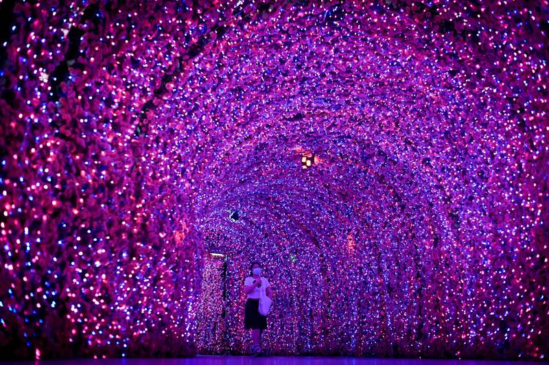A woman walks through a corridor illuminated by colourful lights at the entrance of a mall in Beijing. AFP