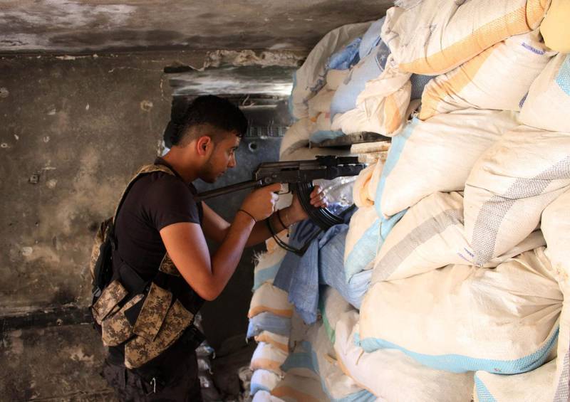 Moawiya Sayasina aims a Kalashnikov assault rifle through sandbags at a fortified position near the frontline in a rebel-held neighbourhood in the southern Syrian city of Daraa. Mohamad Abazeed / AFP