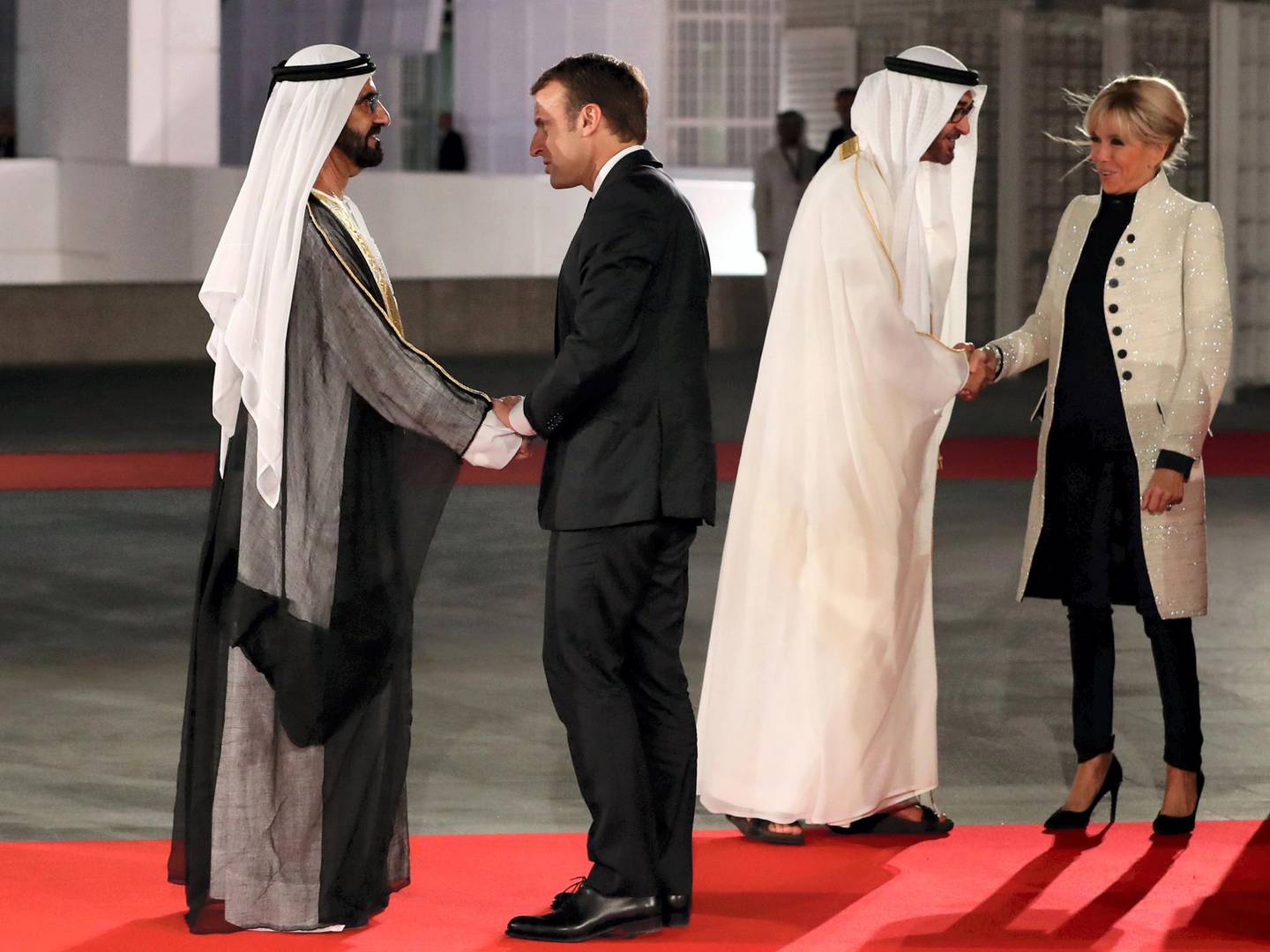 Ruler of Dubai Sheikh Mohammed bin Rashid al-Maktoum (L) shakes hands with French President Emmanuel Macron (C-L) as Abu Dhabi Crown Prince Mohammed bin Zayed Al-Nahyan (2nd R) greets the president's wife, Brigitte Macron, at the entrance of the Louvre Abu Dhabi Museum on November 8, 2017 during its inauguration on Saadiyat island in the Emirati capital. - More than a decade in the making, the Louvre Abu Dhabi is opening its doors bringing the famed name to the Arab world for the first time. (Photo by KARIM SAHIB / AFP)