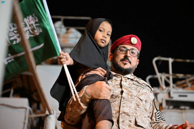A member of the Saudi Navy carries a child from a ship at Jeddah's port during the kingdom's evacuation of civilians from Sudan. Reuters