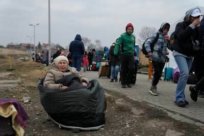 Ludmila Shkarupa, 73, from Ukraine, sits on a chair wrapping herself with a sleeping bag to avoid the cold at the border crossing in Medyka, Poland. AP