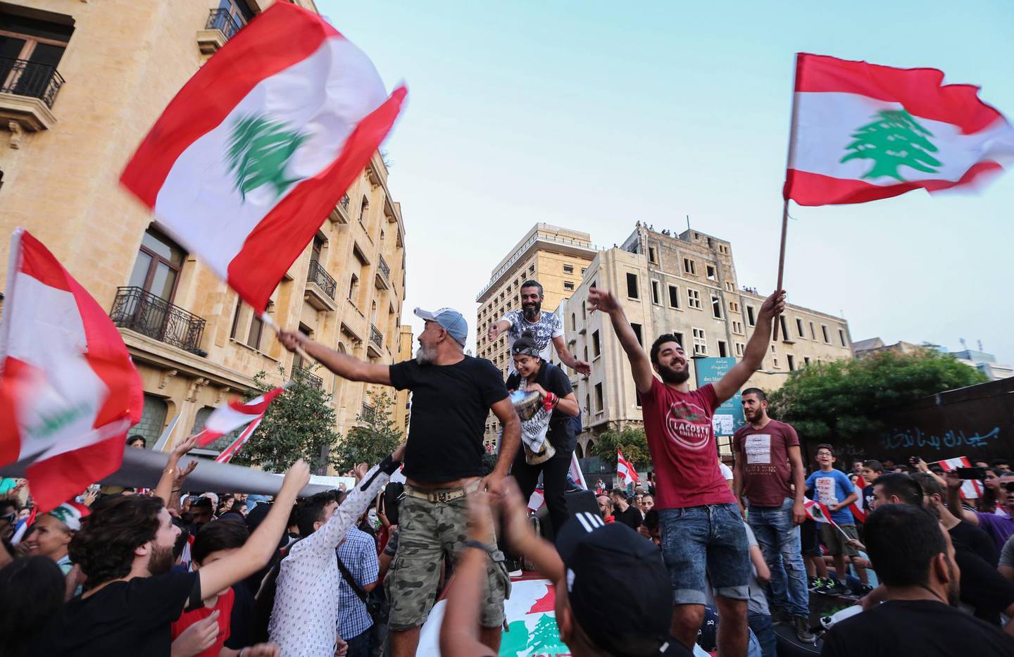 epa07941572 Protesters carry placards, wave Lebanese flags and shout anti-government slogans during a protest in front the Government palace in downtown Beirut, Lebanon, 22 October 2019. Protesters announced they will continue demonstrations and the closure of roads until the resignation of the government and parliament and hold new parliamentary elections one day after Lebanese Prime Minister Saad Hariri announced a series of economic measures adopted by the government and approved the 2020 budget without any new taxes.  EPA/Nabil Mounzer
