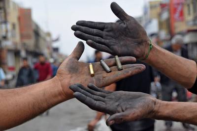 This picture taken on November 28, 2020 shows two men holding up spent bullet casings found at a protest site in Habboubi Square in Iraq's southern city of Nasiriyah in Dhi Qar province. Anti-government protesters defied lockdowns and the threat of violence to demonstrate on November 28 in several Iraqi cities. In the southern hotspot of Nasiriyah, anti-government activists accused supporters of populist Shiite cleric Moqtada Sadr of shooting at them and torching their tents in their main gathering place of Habboubi Square late the day before. Nasiriyah was a major hub for the protest movement that erupted last year against a government seen by demonstrators as corrupt, inept and beholden to neighbouring Iran. / AFP / Asaad NIAZI
