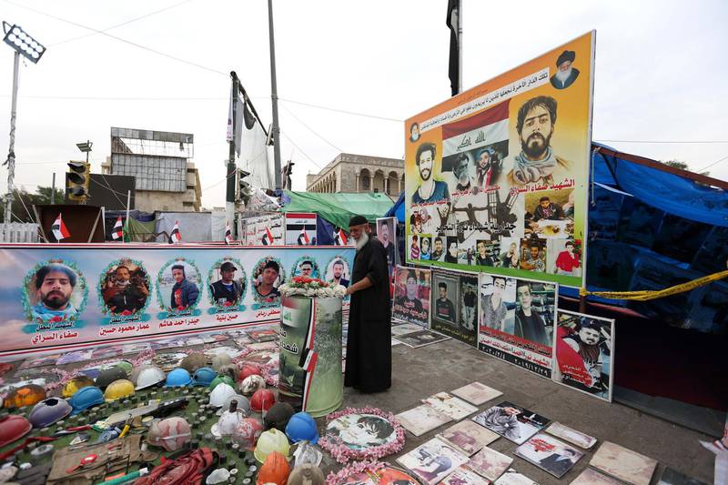 epa08441423 An Iraqi man mourns next to the pictures of  protesters, who were killed in clashes with security forces, during the ongoing protests at the Al Tahrir square at the first day of Eid al-Fitr in central Baghdad , Iraq, 24 May 2020. Iraq's Higher Committee for Health and National Safety has decided to impose a nationwide curfew during the Eid al-Fitr religious holiday to curb the spread of the COVID-19 disease, which is caused by the SARS-CoV-2 coronavirus, after a sustained uptick in new cases.  EPA/AHMED JALIL
