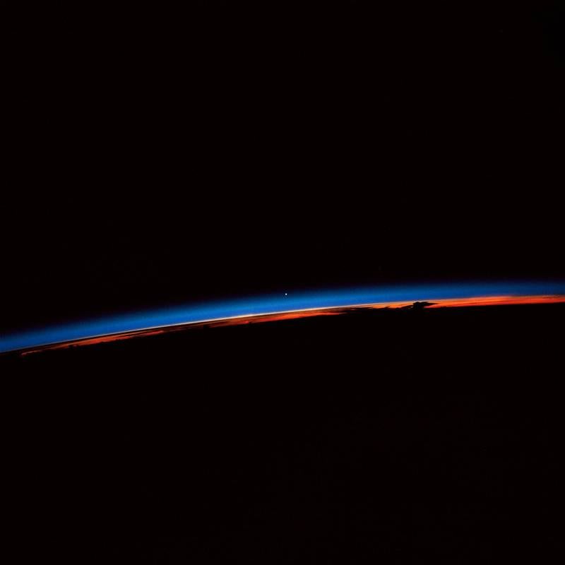 Earth observation captured by crew members onboard Atlantis, Orbiter Vehicle (OV) 104, shows the sunset over the Earth as well as the planet Venus near the center of the frame.