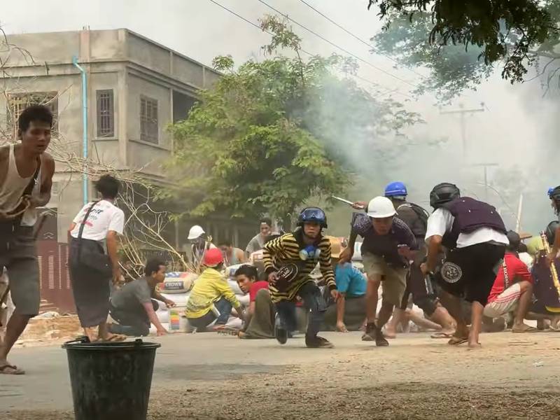 Protesters take cover during clashes with security forces in Monywa. Reuters