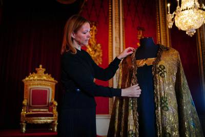 Caroline de Guitaut, deputy surveyor of the King's Works of Art, adjusts the imperial mantle, a part of the coronation vestments, in the Throne Room at Buckingham Palace. AFP