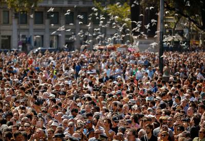 Pigeons fly over crowds gathered for a minute of silence in memory of the terrorist attacks victims in Las Ramblas, Barcelona, Spain, Friday, Aug. 18, 2017. Spanish police on Friday shot and killed five people carrying bomb belts who were connected to the Barcelona van attack that killed at least 13, as the manhunt intensified for the perpetrators of Europe's latest rampage claimed by the Islamic State group. (AP Photo/Francisco Seco)